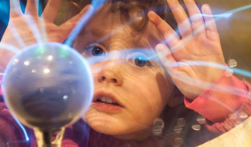 A child looking at a plasma ball exhibit.