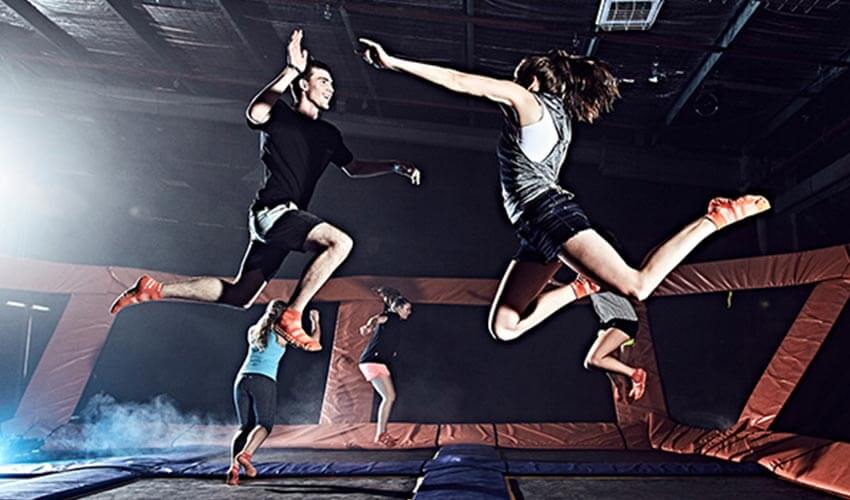 Two people jumping on a trampoline.