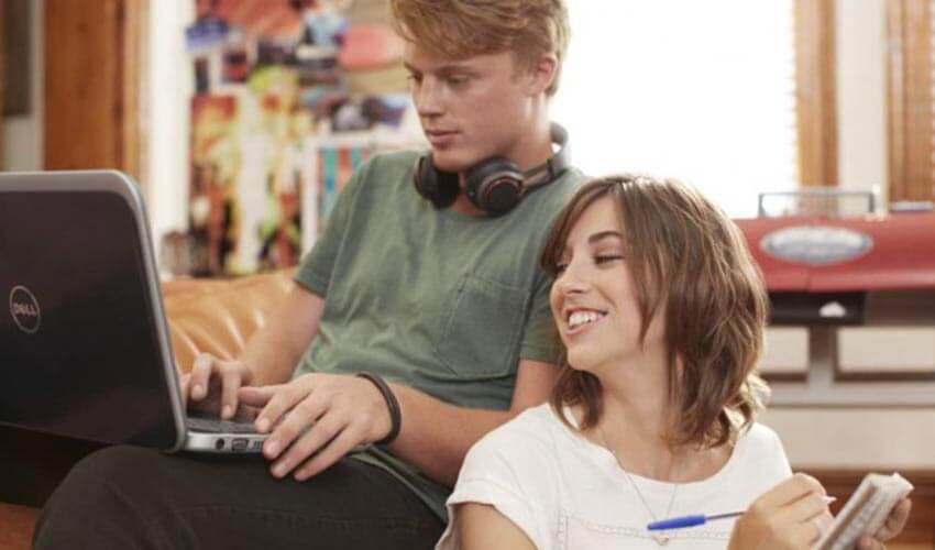 Two students doing homework on a laptop.