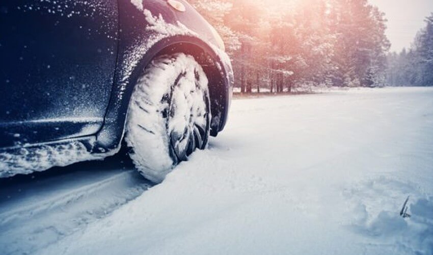 Car tires on winter road covered with snow.
