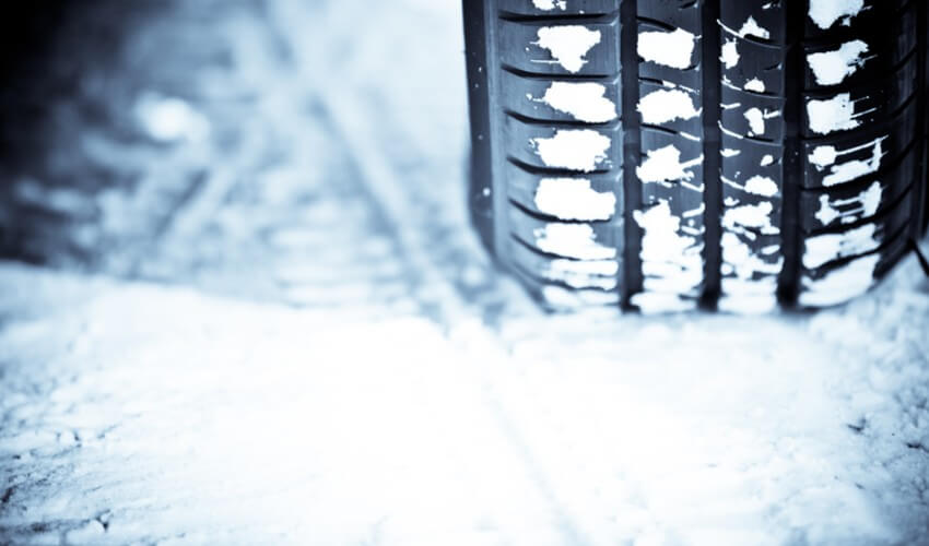 Close up shot of a car's tire in snow.