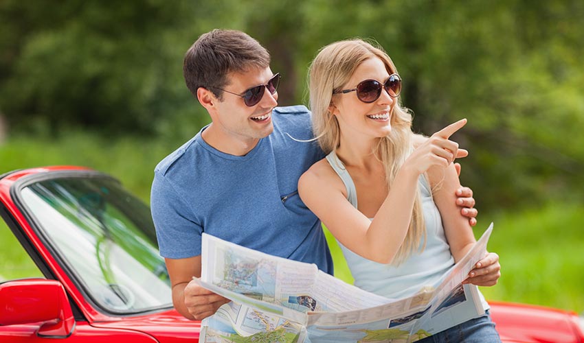 Cheerful young couple on a sunny day reading map.