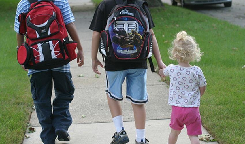 Three young kids walking to school.