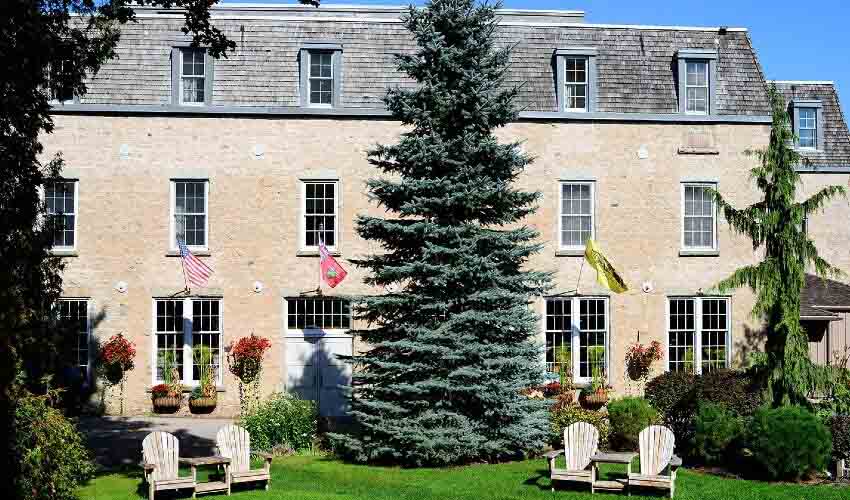 Exterior of Mill Croft Inn and Spa with Muskoka chairs on a sunny day.