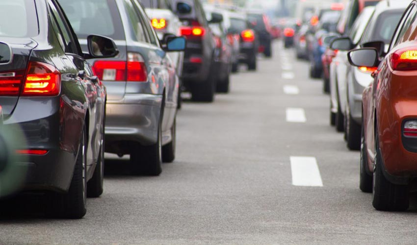 Cars lined up in traffic on a road.