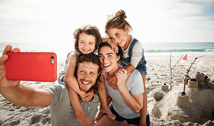 Family taking selfie on beach. 