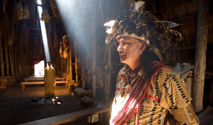 Native American standing inside a longhouse.