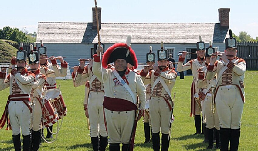 Soldiers dressed in historical costume parading outside.