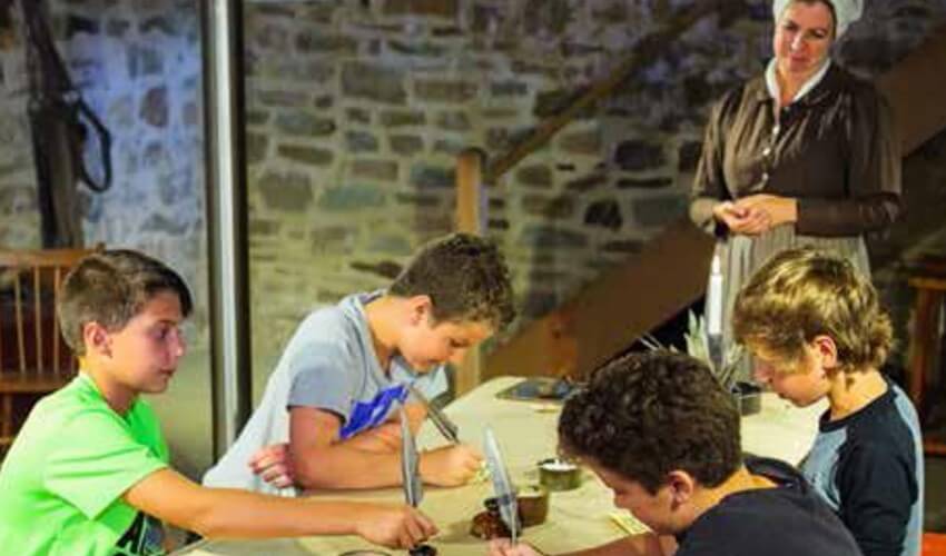 Students writing cursive with ink and quill at Dundurn Castle.