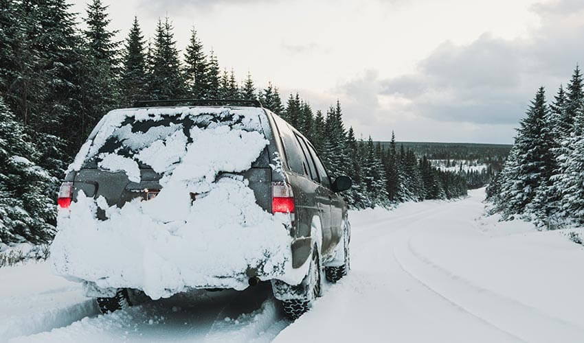 A SUV on a road covered with heavy snow.