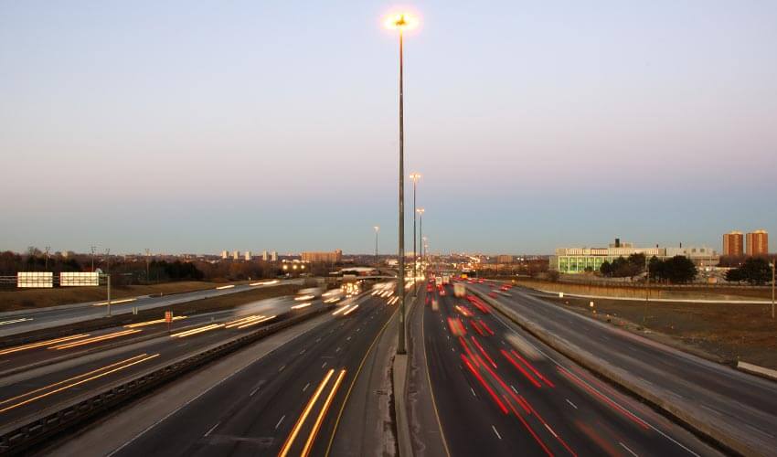 Blurred cars moving along a busy highway at sunset.