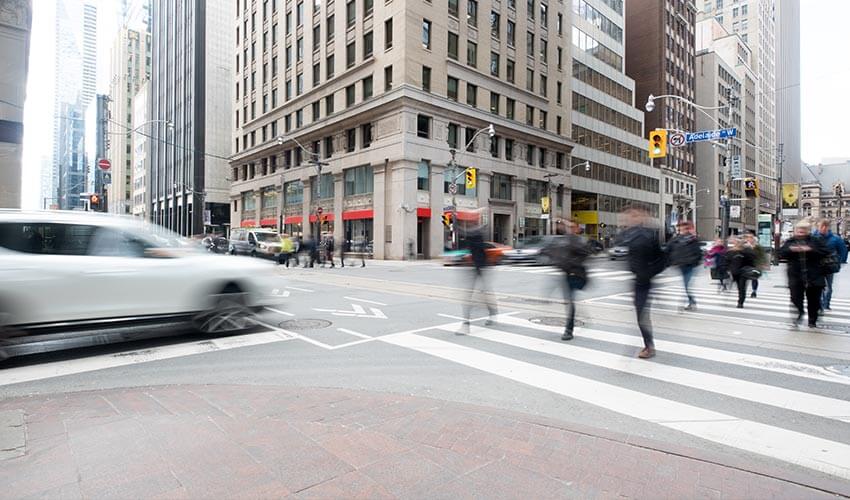 Pedestrians crossing a busy intersection in downtown Toronto.