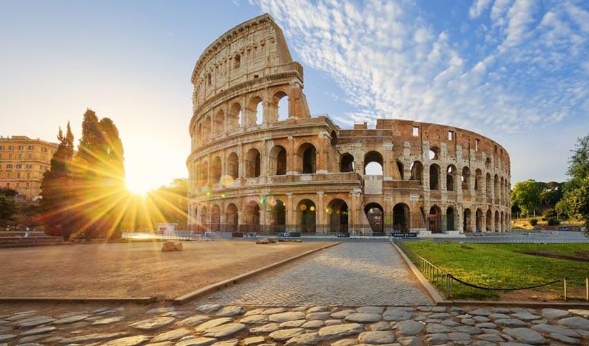 Low angle view of the Colosseum with sun in background.