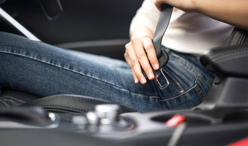Female passenger fastening seat belt in the car.