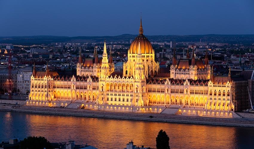 View of the Parliament along the Danube River at night.