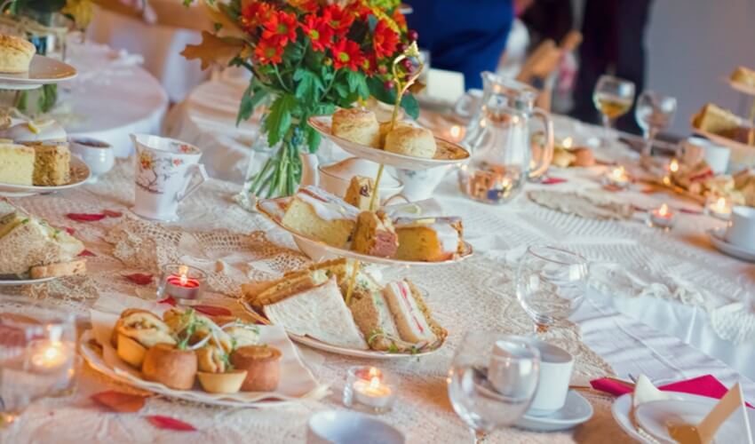 Afternoon tea service with, sandwiches, savory pastries and cakes.