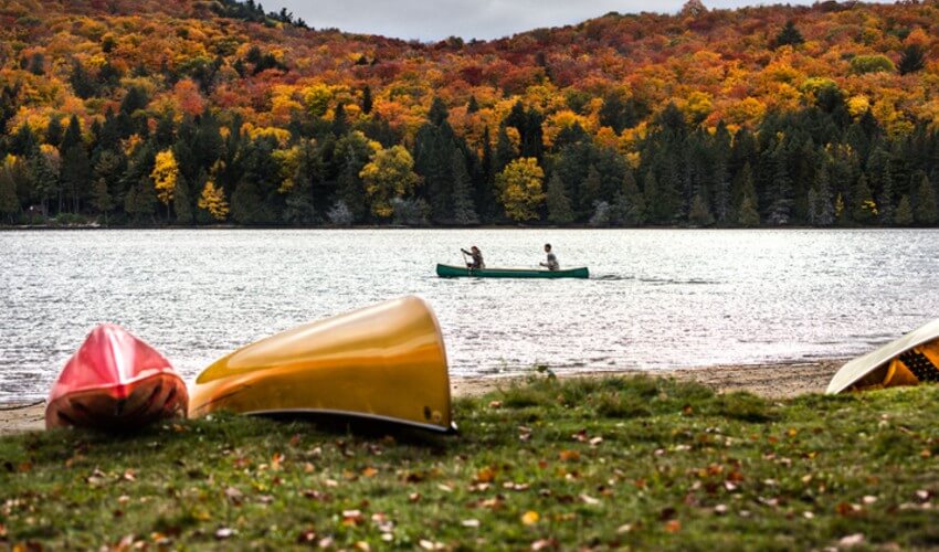 Paddling a canoe with fall colours as a backdrop in Algonquin Park.