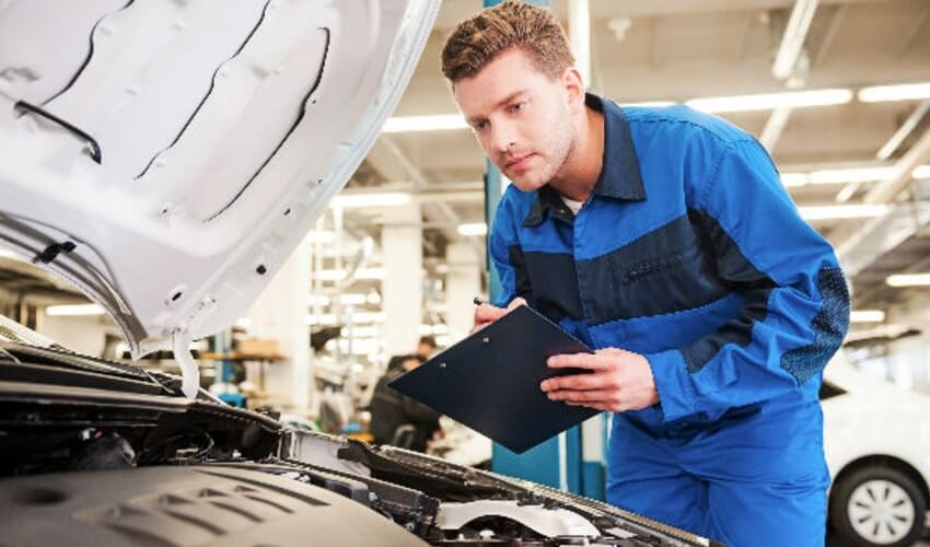 Mechanic looking under a car hood.