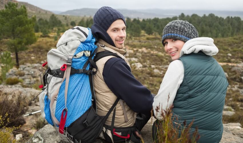 A couple with backpack sitting down to relax while on a hike.