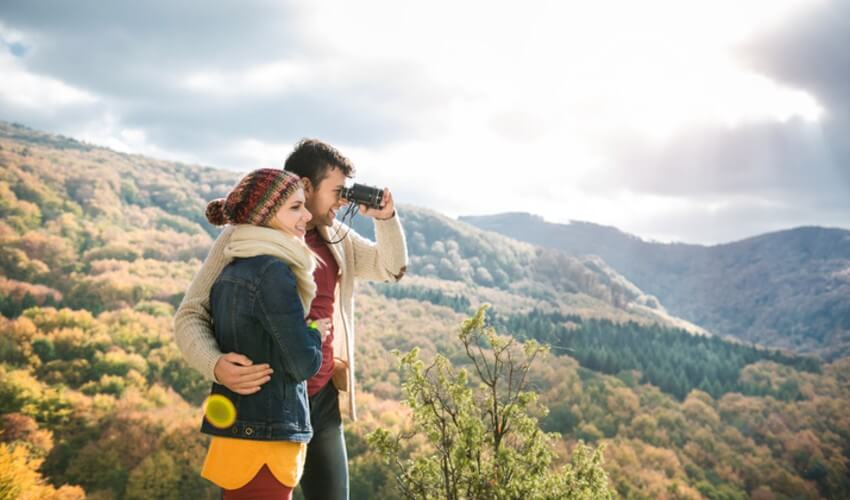 Young couple walking on a sunny autumn day in the forest.