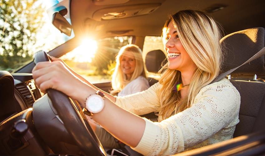 Daughter and mother driving a car going on a family vacation.