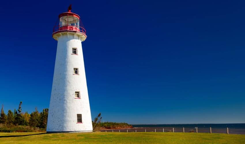 A white lighthouse  with a saturated dark blue sky.