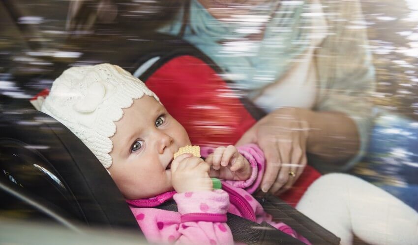 Mother helping a baby in a car seat.