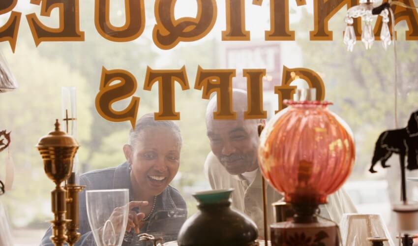 Man and woman looking through window of antique shop.