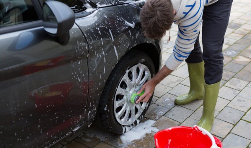 Close up of a person washing car wheels.