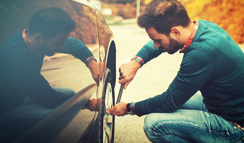 A man tightening the lug nuts on a wheel of car.