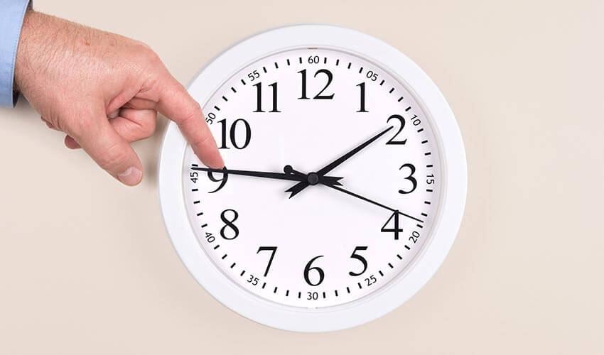 A hand adjusting the minute hand of a clock