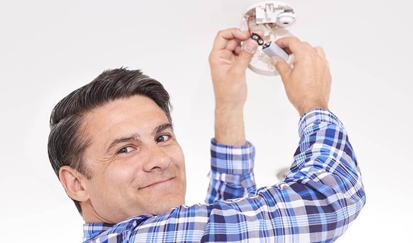 A man changing the battery of a smoke detector