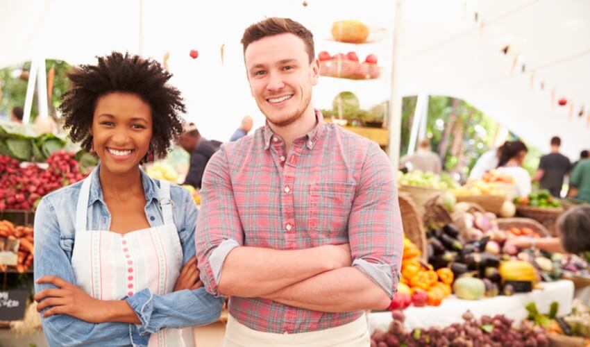 A man and woman standing in front of a farmer’s market.