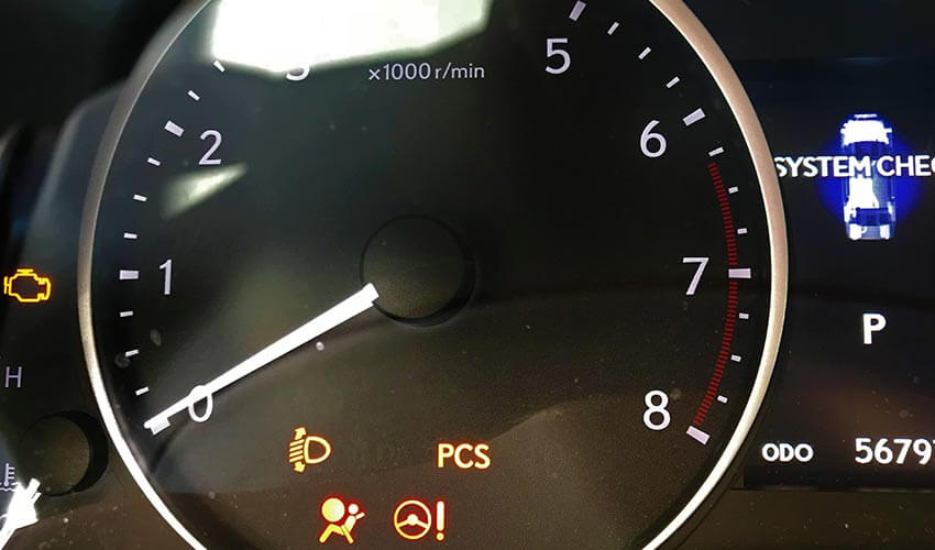 A car's tachometer with some warning lights activated.