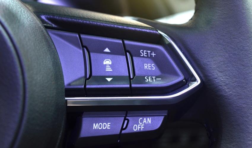 Buttons on a car's steering wheel for driver to enable cruise control.