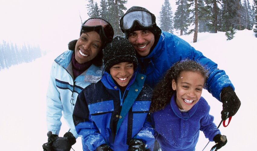 Family of four having a fun time skiing outdoors.