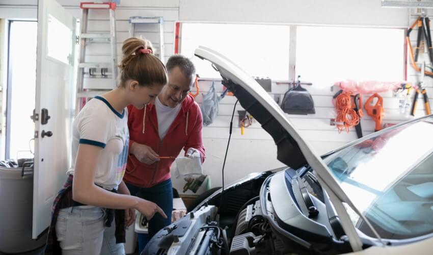 Father and daughter checking car engine oil.