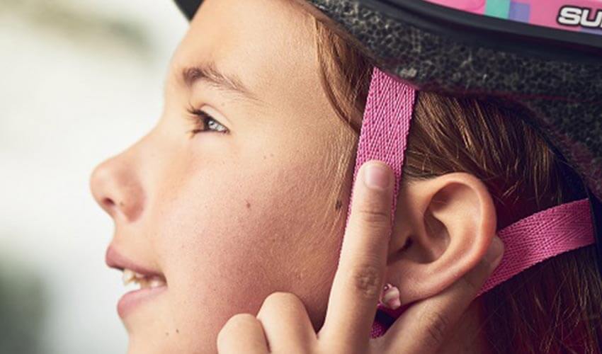 Close up of a child checking if a bike helmet is securely fastened.