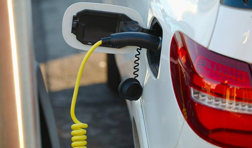 A white electric vehicle plugged into a charging station.