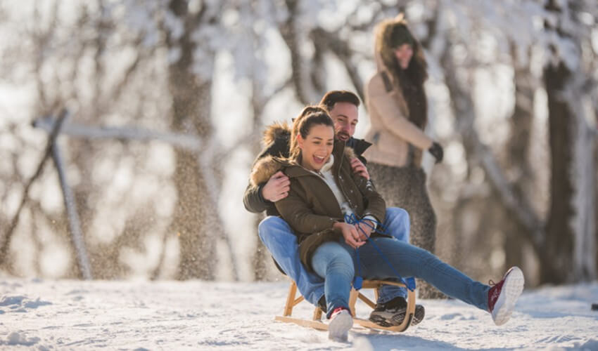 A couple sledding on a winter day.