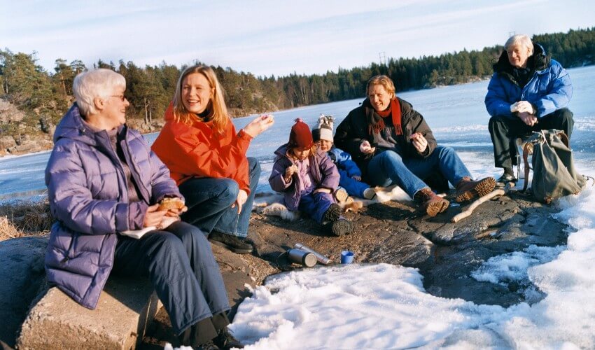 Family of four and grandparents resting outdoors on a wintery day.