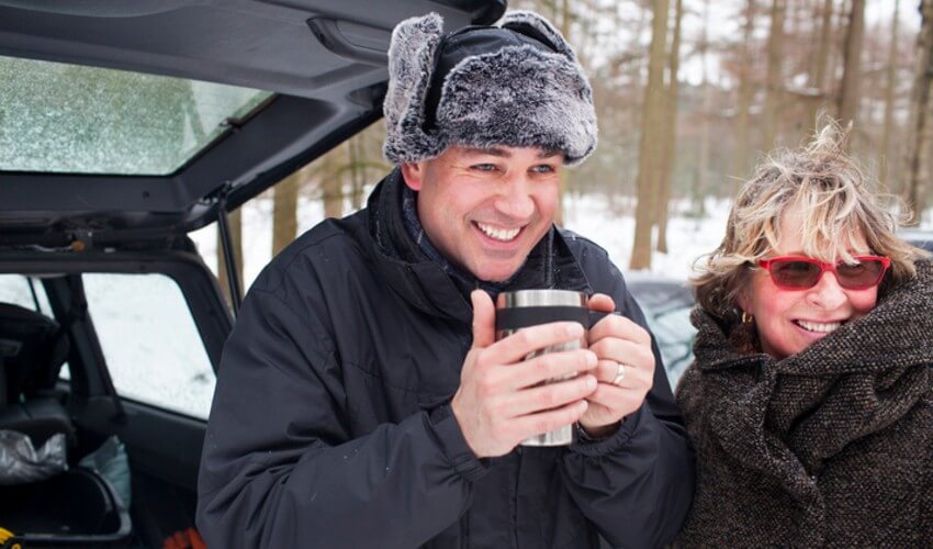 Mother and adult son having a hot drink outside in winter.