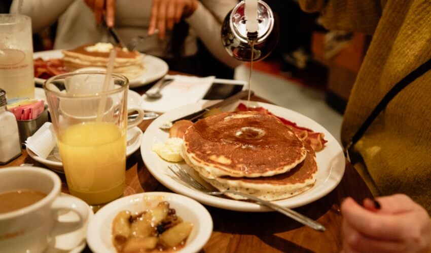 Pouring maple syrup on pancakes.
