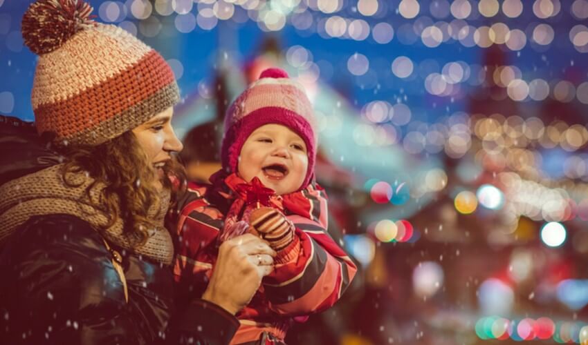 Mother and baby daughter enjoying Christmas time at a market.