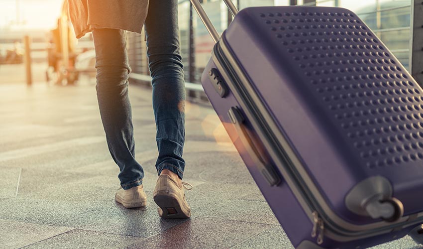 A person pulling a suitcase in an airport.