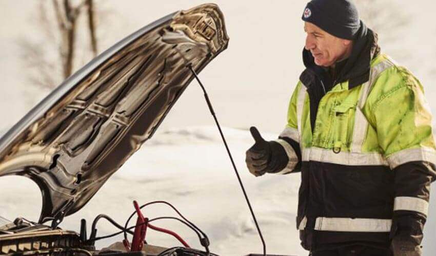 CAA driver jump starting a car giving a thumbs up.