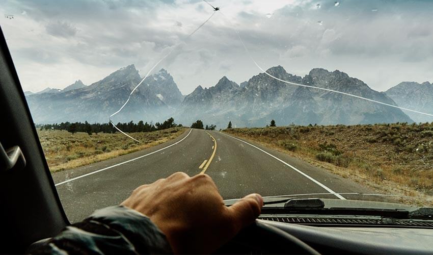 Man driving a car with a damaged windshield.