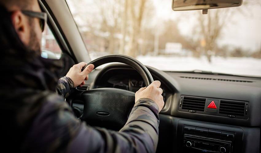 A man driving a car in winter.