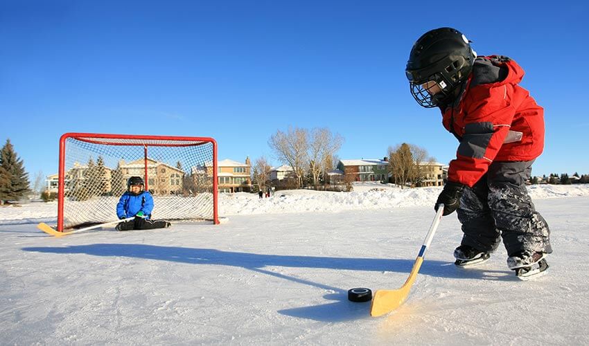 Two kids playing hockey outdoors.