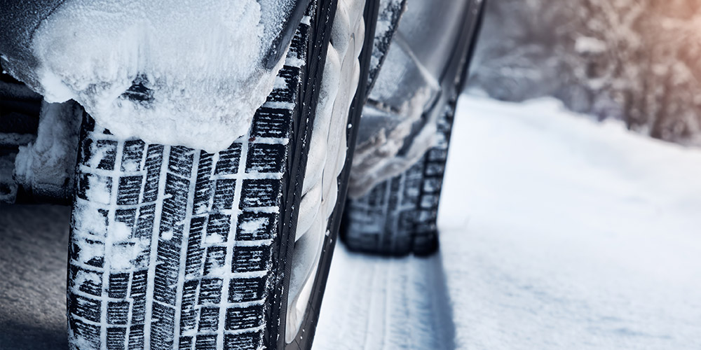 Closeup shot of winter car tires on a snowy, winter day, with snow between the treads